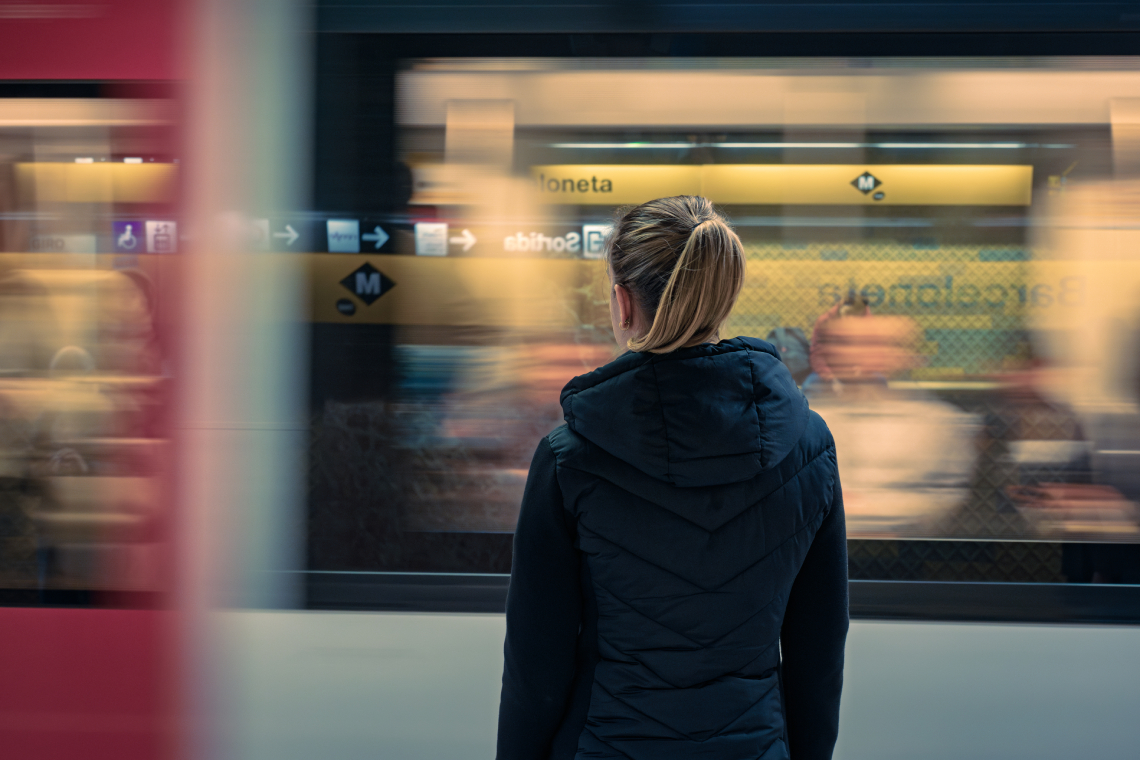 Noia veient el metro passar a la parade de Barceloneta