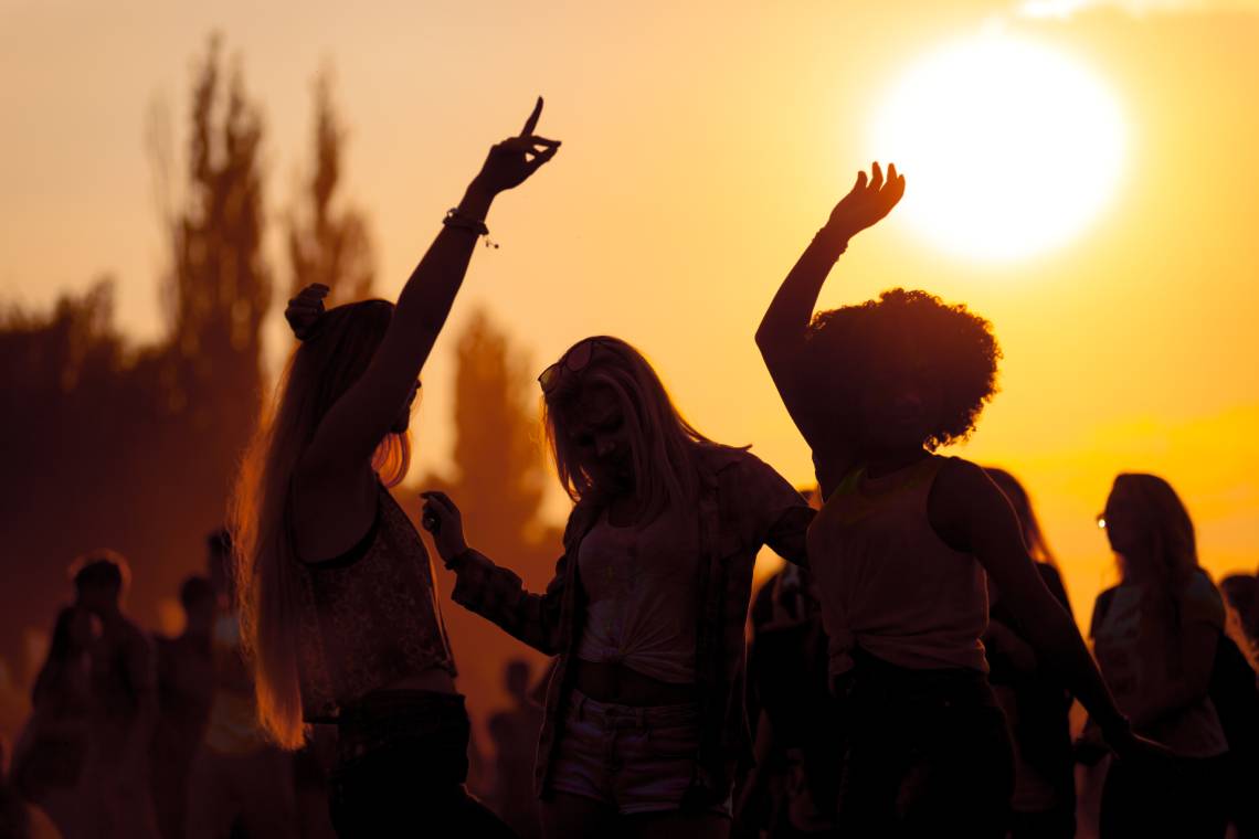 Tres noies de festa a un festival de música amb el sol de fons