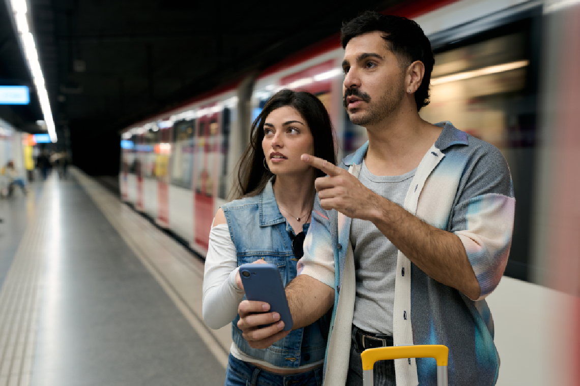 Dos turistas dudando delante de un metro pasando en Barcelona