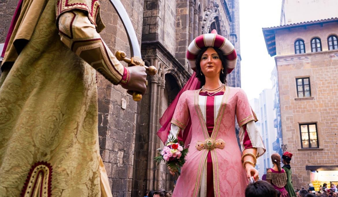 Imatge dels gegants del Pi dansant per Barcelona al març, el pla es des de darrere del gegant observant a la geganta avançar cap a ell.