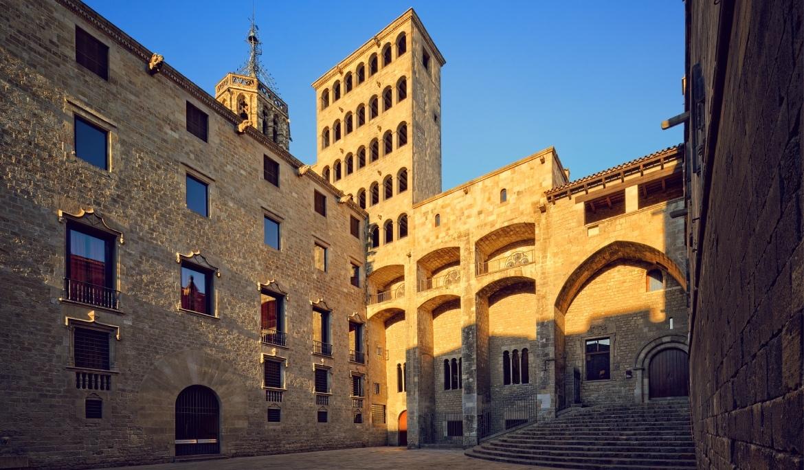 Imagen de la plaza del MUHBA durante la golden hour. Los edificios de piedra brillan con un contraste de luces y sombras que hace imprescindible visitarla en una ruta por Barcelona en 3 días.