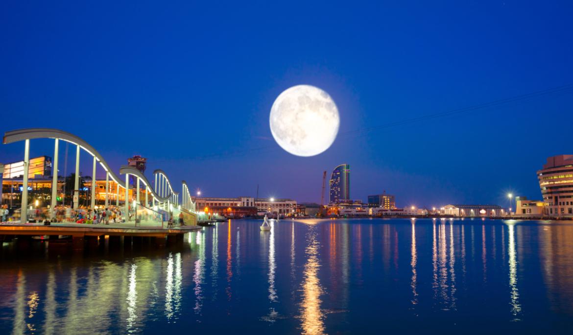 Imagen del Port Vell de Barcelona de noche, con luna llena.