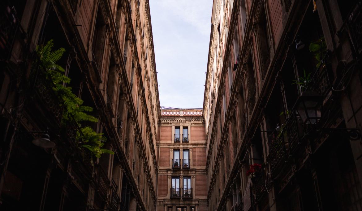 A low-angle shot of the passage, looking up at a small square of sky framed by symmetrical balconies.