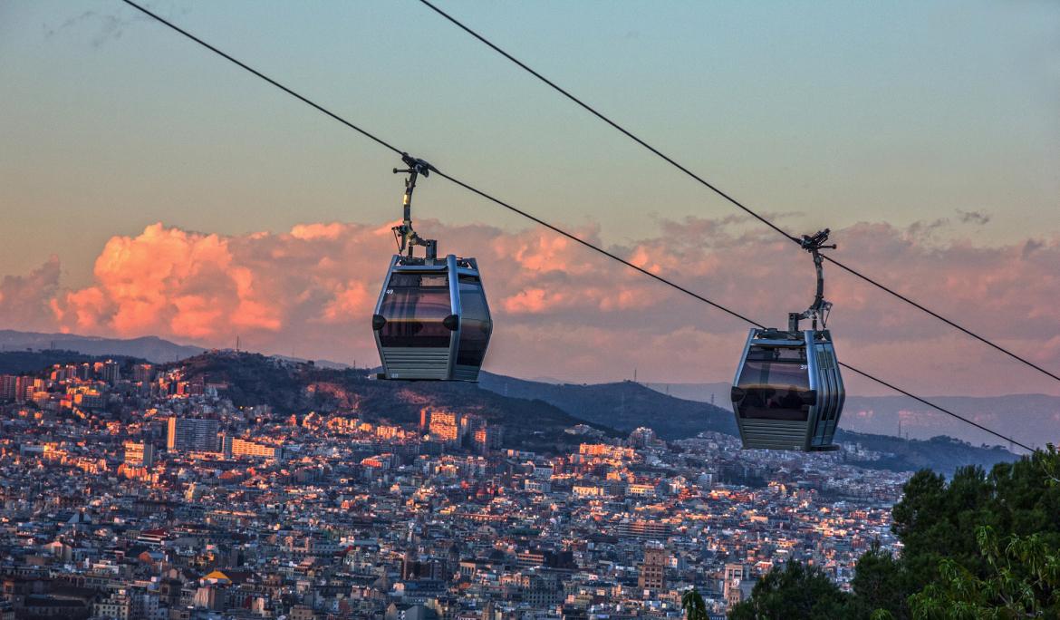 Sunset at Montjuïc with two cable car cabins crossing each other.