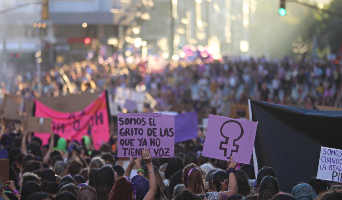 Image of an 8M demonstration in Barcelona, with large crowds in the streets holding signs with drawings and protest messages.