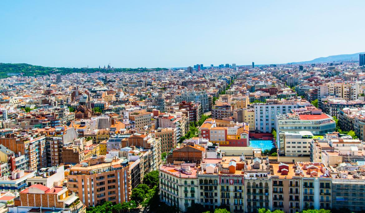 Aquí tens la traducció al castellà i a l'anglès:  Castellà: "Vista del trazado del Eixample desde las alturas."  Anglès: "Aerial view of the Eixample district's grid pattern