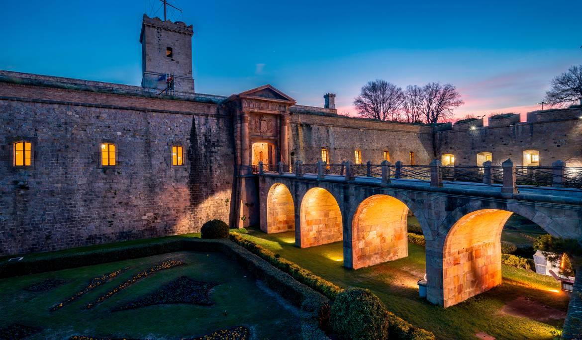 Imatge del Castell de Montjuïc de nit iluminat amb llums artificials.