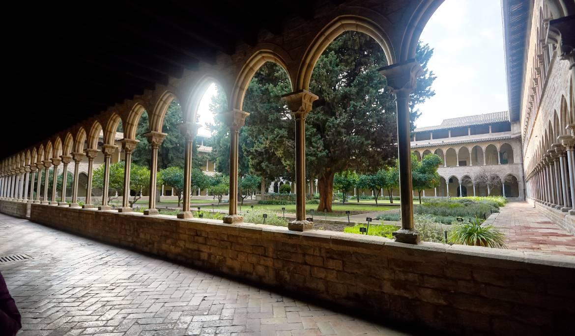 Imagen del claustro del monasterio de Pedralbes con la luz del dia entrando por los arcos de piedra.