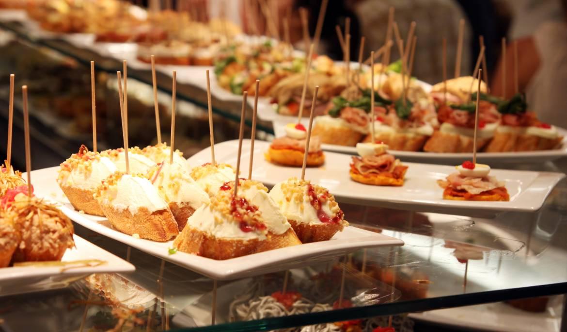 Imagen de una taberna tradicional con su barra llena de pinchos y tapas.