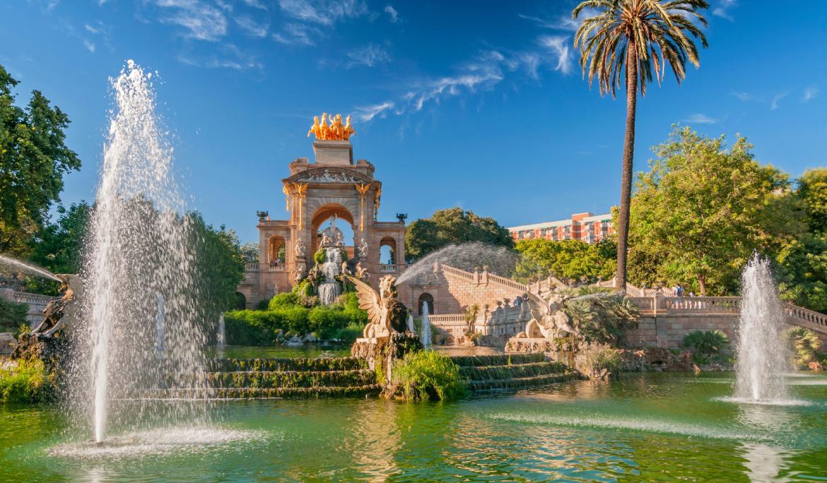 mage of people strolling along the leafy pathways of Ciutadella Park in late summer.