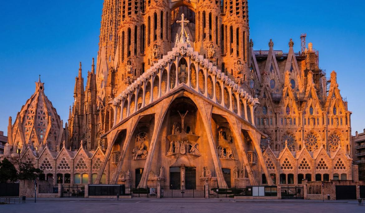 Image of the soaring towers and facade of the Sagrada Família basilica against a blue sky.