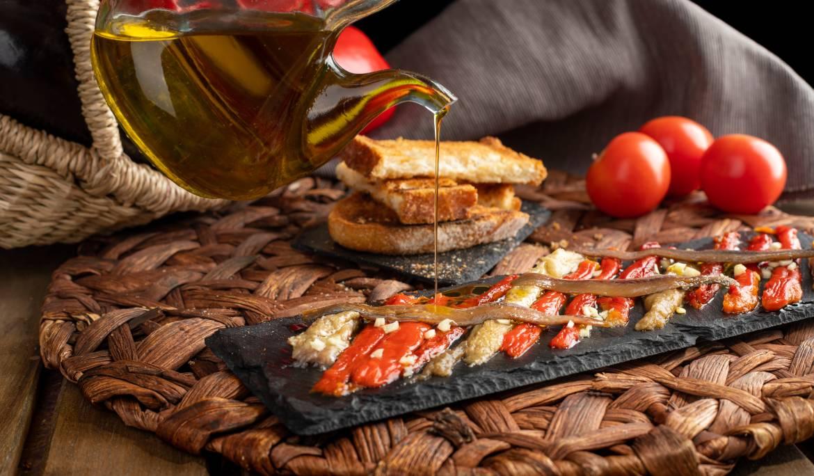 Image of a plate of escalivada, traditional Catalan dish of roasted vegetables (peppers and eggplants) served cold and drizzled with olive oil.