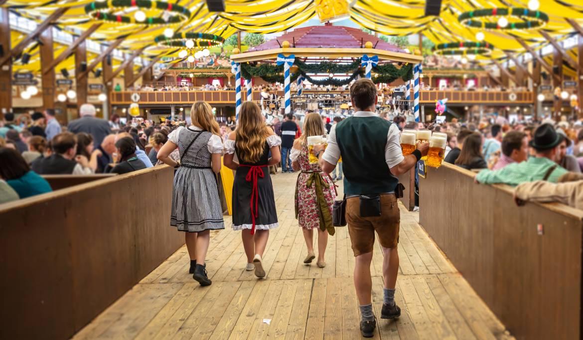Image of festive beer steins and traditional Bavarian pretzels on a wooden table.