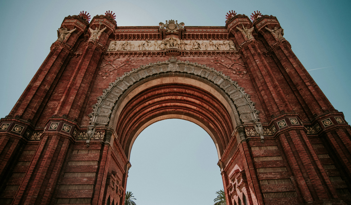 Imagen del arco de ladrillo visto del Arc de Triomf destacando bajo el cielo de Barcelona.