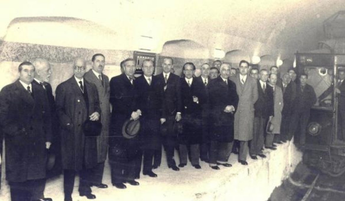 Black-and-white historic photograph of the station opening ceremony and early passengers.