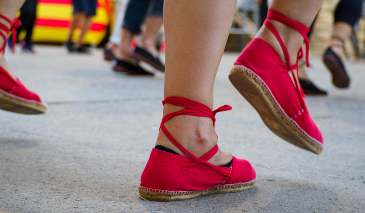 Imagen en detalle de los pies de un bailarín vistiendo alpargatas tradicionales catalanas atadas sobre el suelo.