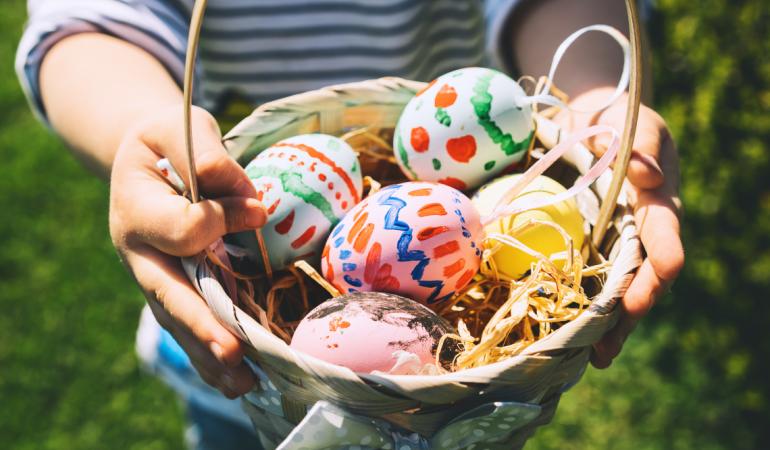 Child holding a basket full of colorful Easter eggs.