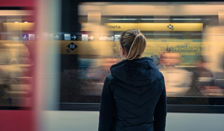 Noia veient el metro passar a la parade de Barceloneta