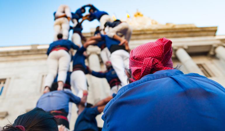 Castellers vestidos de azul subiendo un castillo humano.